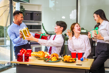 Festive office Christmas party with friends and colleagues celebrating after work. Asian business people wear Santa hats, enjoy grilled chicken, drinks, and gifts,  indoor scene with holiday lights.