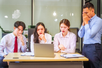 Two men and two women, including boss and employees, discuss recent mistake. Expressions of disappointment and constructive criticism create a tense, reflective atmosphere around laptops and desks.