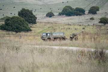 British army bae systems, Puch, Daimler, Pinzgauer High-Mobility All-Terrain 6x6 vehicle towing a 105mm Light Artillery Gun on a military exercise © Martin