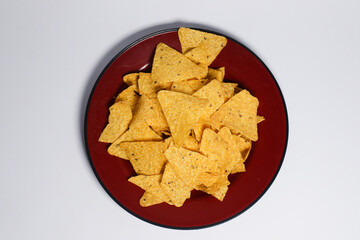 The chips have a triangular shape with a rough texture and small black seasoning specks visible on the surface. They appear crispy and ready to eat, with some chips overlapping each other. 