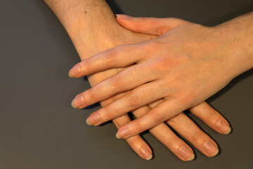 Hands with natural nails. No nail polish. Gray background.