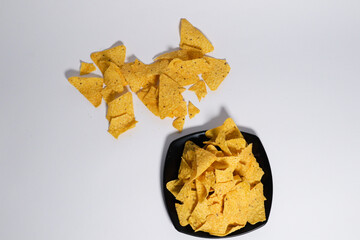 The chips have a triangular shape with a rough texture and small black seasoning specks visible on the surface. They appear crispy and ready to eat, with some chips overlapping each other. 