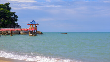 A Colorful Pagoda-style Gazebo Stands On Stilts In The Middle Of The Calm Sea, Surrounded By A Bright Blue Sky