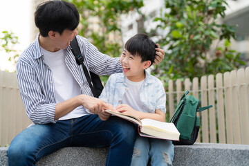 In a vibrant garden, a happy boy reads a book with his father. Their cheerful smiles capture the essence of family, fun, and learning during a beautiful summer day outdoors.