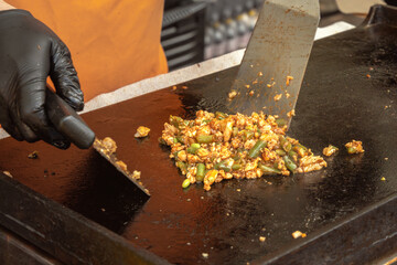 Pieces of meat with onions and vegetables are fried on a metal sheet as a filling for pita bread, sandwich or burrito. Street food. Fast food. Close-up