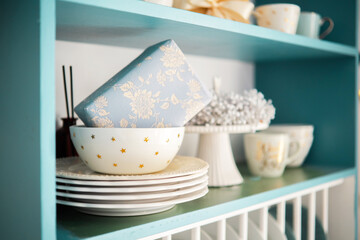 Decorative kitchen shelf with elegant tableware and a wrapped gift