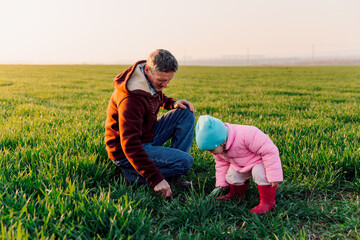 Grandfather and granddaughter in the field with sunlight