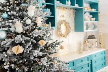 Festively decorated Christmas tree in a cozy kitchen with teal cabinetry