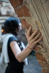 person gently touches weathered brick wall in ancient building, captured in soft natural light that creates atmosphere of tranquility and exploration