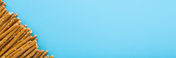 Long thin dry cracker sticks on light blue table background. Pastel color. Closeup. Salty snack. Wide banner. Empty place for text. Top down view.