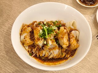 Shrimp and pork wontons with egg noodles in spicy sauce on wooden table at Chinese restaurant. Chinese food menu