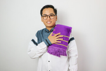 Moslem Asian man looking to the camera with happy face expression while waving his hand to greet others