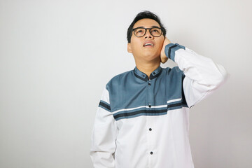 Young asian muslim man wearing moslem clothes and prayer mats in his shoulder. He is on the call to prayer or adzan