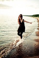 Fototapeta premium Woman Joyfully Running on the Beach at Sunset