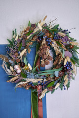modern Christmas wreath with needles and dried flowers on a light background