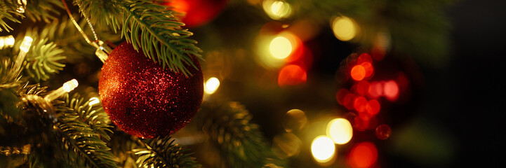 Close-up of Christmas tree with red balls and bokeh in the background. Background with copy space for holiday design. © Kaplitskaya Love