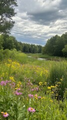Fototapeta premium A vibrant landscape featuring blooming wildflowers beside a tranquil river during cloudy weather in early summer