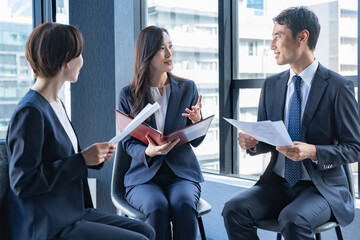 資料を持ち会議をするスーツを着た男女