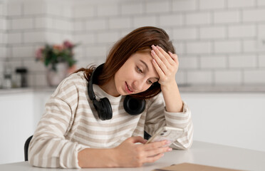Teenage Girl Reads Messages On Phone At Home In Bright Kitchen