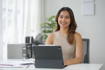 Confident woman working on a tablet at a modern office desk. Bright and productive workspace with a cheerful atmosphere.