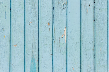 Old blue wooden wall. Old wood texture. Old light blue wooden fence. Background photo of vintage. Weathered light blue unevenly painted vertical hardwood plank wall with painted nails in it.