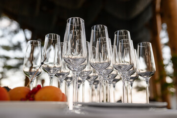 Close-up shot of several empty champagne glasses arranged in a row on a white table. A plate of fruit, including apricots and berries, is in the foreground, ready for a special event.