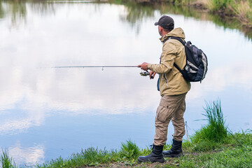 A man catches fish with a spinning rod on the river bank