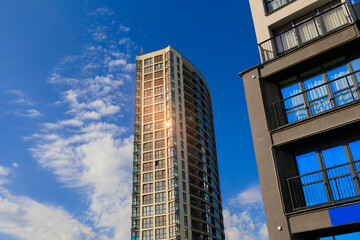 Fototapeta premium Modern buildings, walls and windows, reflections and sun rays. City view on a sunny day. 