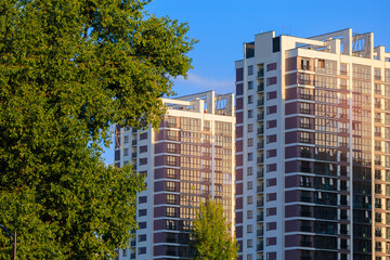Modern buildings, walls and windows, reflections and sun rays. City view on a sunny day. 
