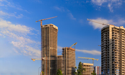 Construction cranes and new buildings, construction work of modern skyscrapers on a sunny day.