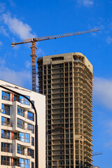 Fototapeta premium Construction cranes and new buildings, construction work of modern skyscrapers on a sunny day.