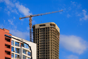 Construction cranes and new buildings, construction work of modern skyscrapers on a sunny day.
