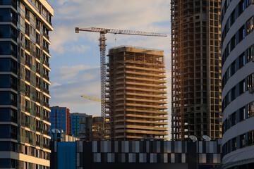Construction cranes and new buildings, construction work of modern skyscrapers on a sunny day.