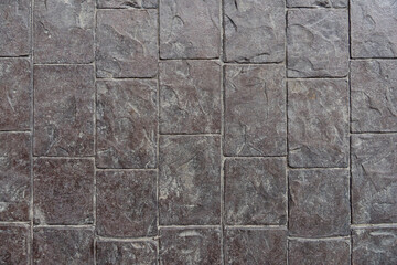 Above of cement floor with lines cut on the floor are a brick pattern. There is dust and dirt along the grooves from use.