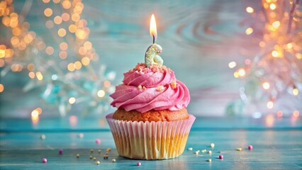 A single pink cupcake topped with a lit candle, sitting on a teal wooden surface, surrounded by sprinkles and bokeh lights.