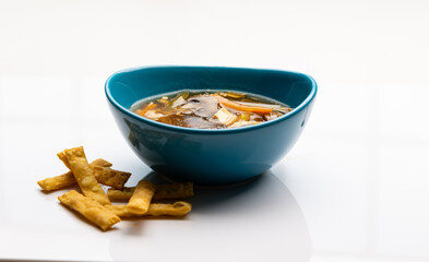 Chinese hot and sour soup served with asian crackers on white background