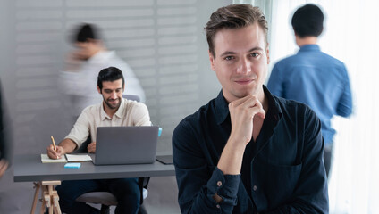 Confidence and happy smiling businessman portrait with blur motion background of his colleague and business team working in office. Office worker teamwork and positive workplace concept. Prudent