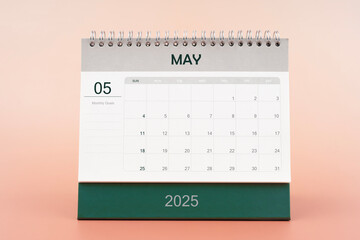 May 2025 desk calendar isolated in pink background.