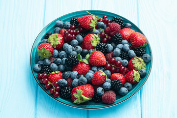 Mix of ripe colorful berries in bowl photography . Blueberry , strawberry , raspberry , blackberry and red currant . Top view