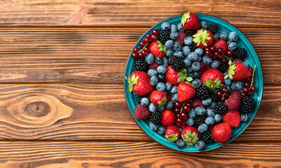 Mix of ripe colorful berries in bowl photography . Blueberry , strawberry , raspberry , blackberry and red currant . Top view