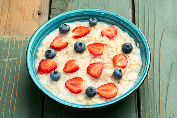 Homemade breakfast . Oatmeal with milk and berries . Top view