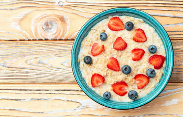Homemade breakfast . Oatmeal with milk and berries . Top view