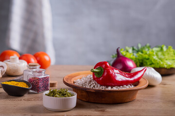 Fresh vegetables, herbs and cereals lie on a wooden countertop in the kitchen