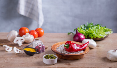 Fresh vegetables, herbs and cereals lie on a wooden countertop in the kitchen