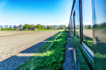 Small steam tram locomotive driving through the Dutch countryside