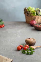 Fresh vegetables and greens lie on a gray table. Space for text