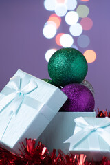 Open gift box with Christmas balls coming out from inside and bokeh lights with copy space