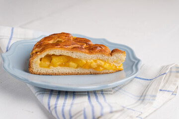A piece of yeast pie with apple filling on a light background