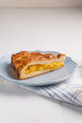 A piece of yeast pie with apple filling on a light background