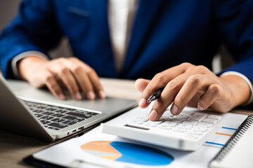 Business finance and budget management, Businessman using calculator and analyzing invoices and tax documents to manage company finances, Budget, Monthly expenses on desk with documents and reports.